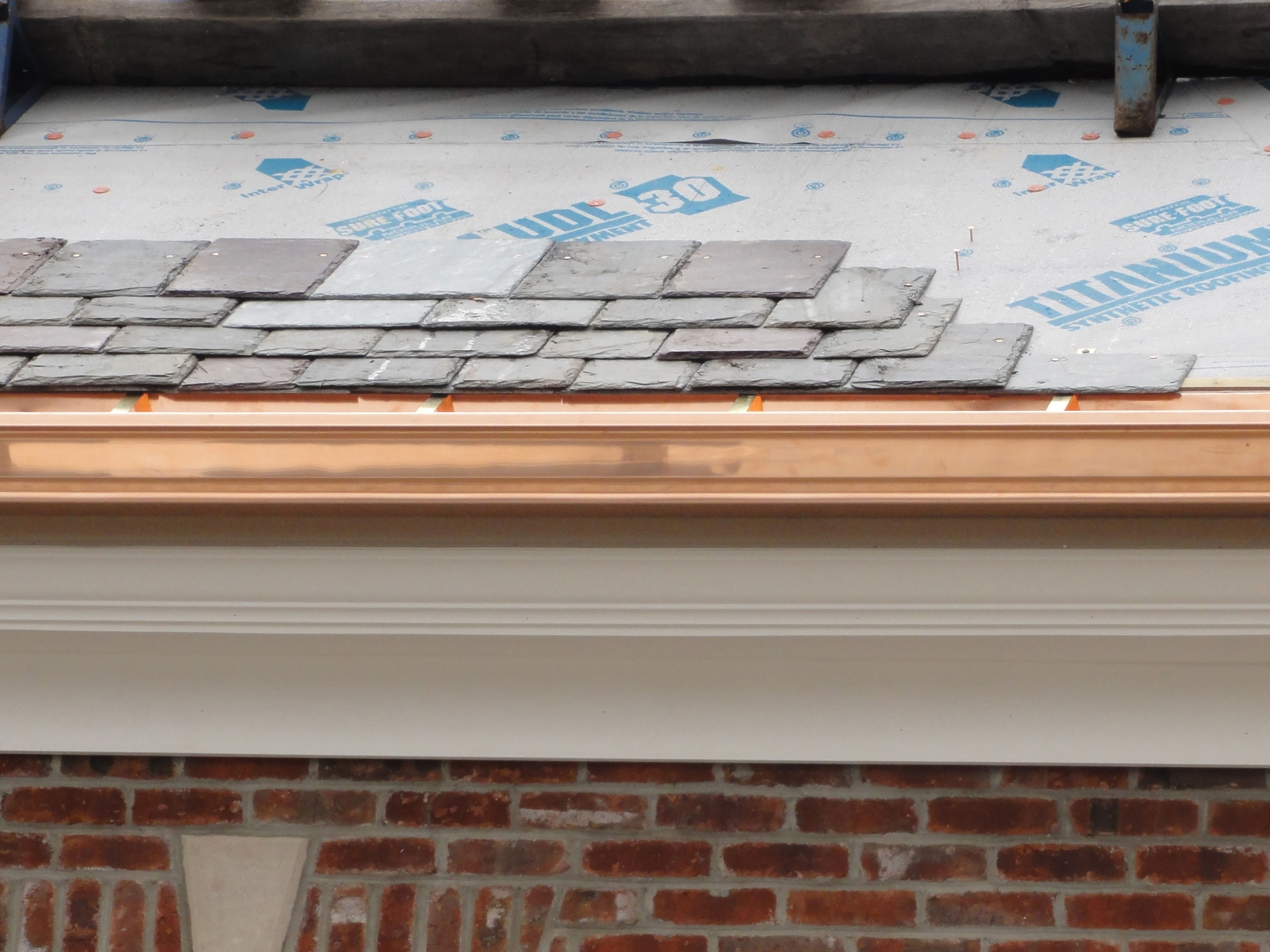 shiny copper gutters with new slate roof